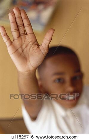 Stock Photograph - Child raising hand in classroom. Fotosearch