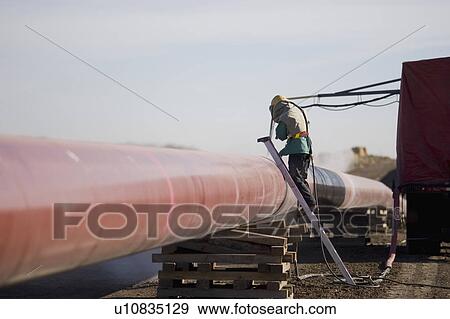 Stock Photo - Construction worker cleaning pipeline. Fotosearch