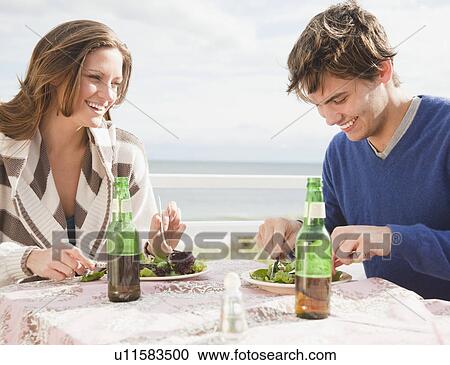 Stock Image - Couple eating at the beach. Fotosearch
