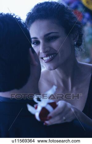 Picture - Couple embrace with gift in hand. Fotosearch