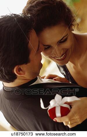 Stock Image - Couple embrace with gift in hand. Fotosearch