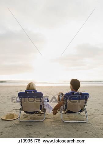 Couple relaxing at the beach View Large Photo Image Stock Photo - Couple relaxing at the beach. Fotosearch