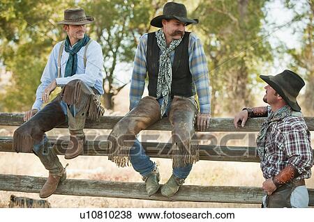Stock Photo - Cowboys sitting on fence. Fotosearch