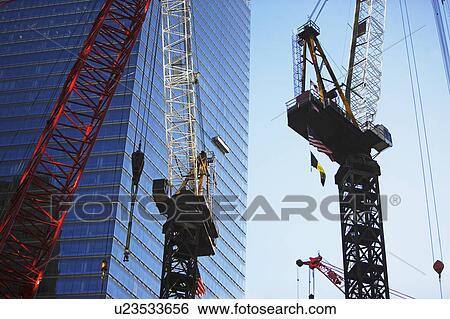 Stock Photograph - Cranes beside skyscraper. Fotosearch