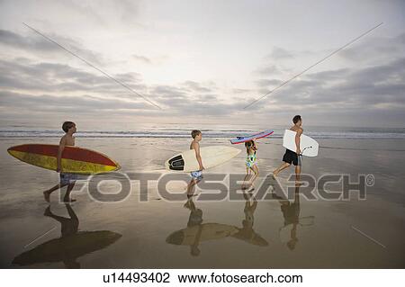 Stock Image - Family carrying surfboards. Fotosearch