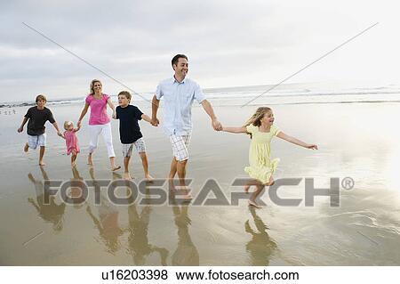 Stock Photo - Family holding hands in ocean. Fotosearch