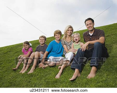 Stock Image - Family sitting on grass. Fotosearch