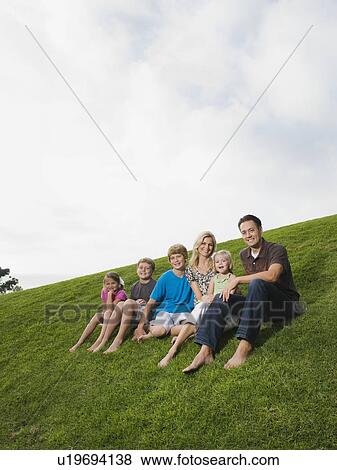 Stock Photo - Family sitting on grass. Fotosearch