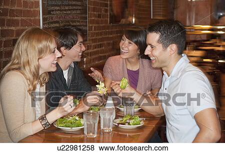 Stock Photo - Friends eating at restaurant. Fotosearch