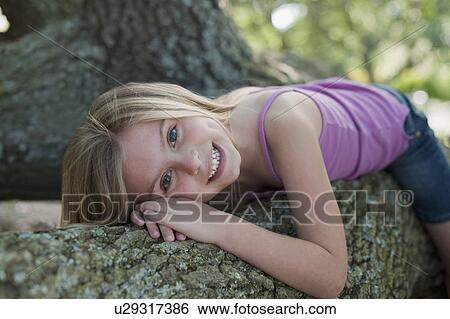 Girl lying down on tree View Large Photo Image Stock Photograph - Girl lying down on tree. Fotosearch