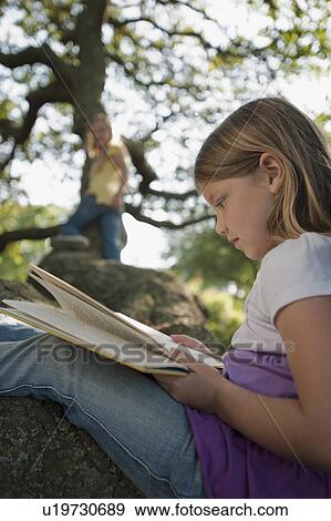 Stock Photo - Girl reading book in tree. Fotosearch