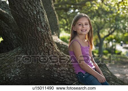 Stock Image - Girl sitting on tree. Fotosearch