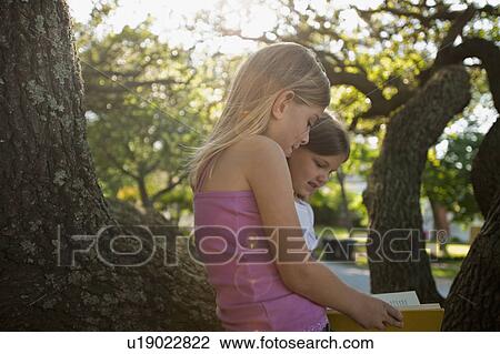 Stock Image - Girls reading outside. Fotosearch