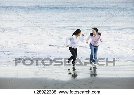 Stock Photo - Girls running on beach. Fotosearch