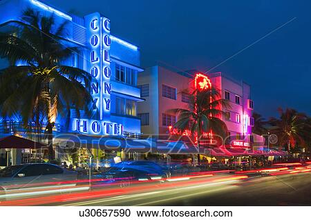 Stock Image - Illuminated buildings and car lights at night. Fotosearch