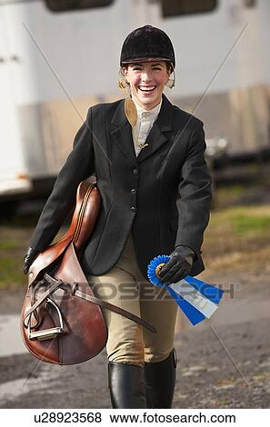 Stock Photo - Jockey walking with saddle and ribbon. Fotosearch