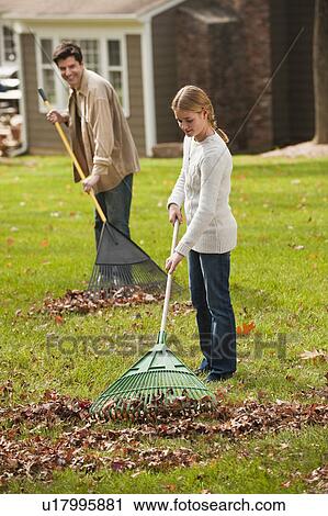 Stock Image - Man and girl raking leaves. Fotosearch