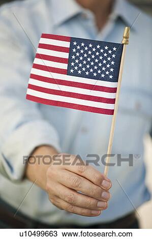 Stock Image - Man carrying American flag. Fotosearch