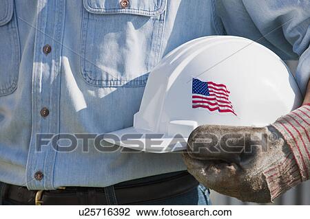 Stock Image - Man holding hardhat. Fotosearch