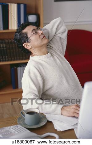 Stock Photo - Man stretching at desk. Fotosearch
