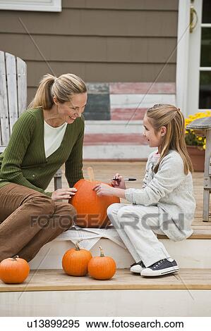 Stock Photography - Mother and daughter carving pumpkin. Fotosearch