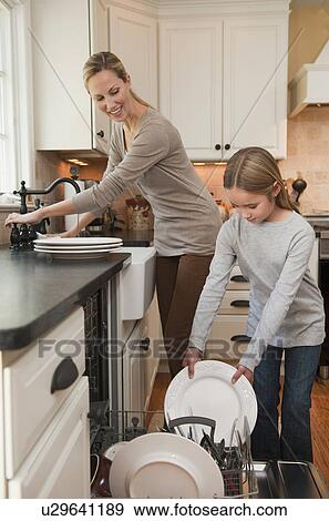 Stock Photo - Mother and daughter loading dishwasher. Fotosearch
