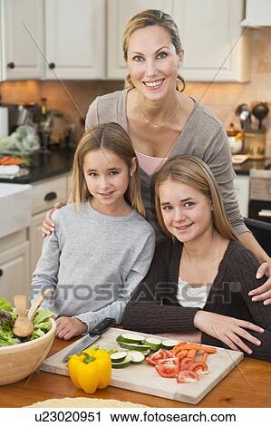 Stock Image - Mother and daughters making salad. Fotosearch