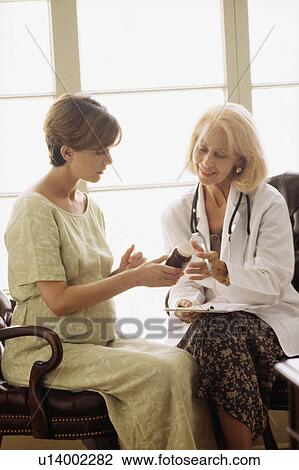 Stock Image - Obstetrician talking to pregnant woman. Fotosearch