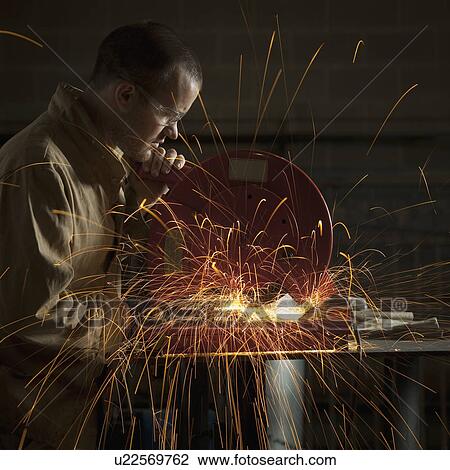 Stock Image - Steel grinder working in metal shop. Fotosearch