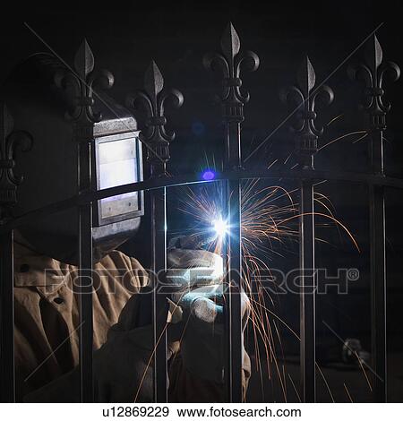 Stock Photo - Steel worker welding a fence. Fotosearch
