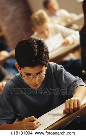 Student writing at desk in classroom View Large Photo Image Picture - Student writing at desk in classroom. Fotosearch