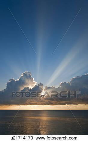 Stock Image - Sunset behind clouds. Fotosearch