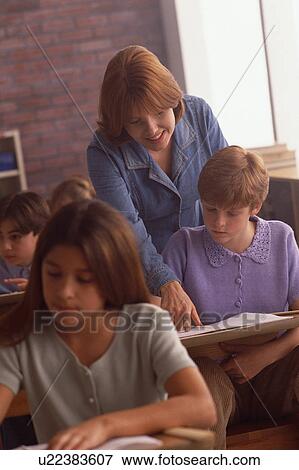 Stock Photo - Teacher helping student in classroom. Fotosearch