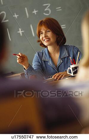 Teacher sitting at desk in classroom View Large Photo Image Stock Photo - Teacher sitting at desk in classroom. Fotosearch