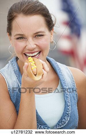 Stock Image - Woman eating hotdog. Fotosearch