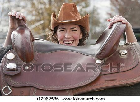 Woman holding saddle View Large Photo Image Stock Photograph - Woman holding saddle. Fotosearch