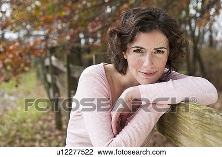 Stock Image - Woman leaning on fence. Fotosearch