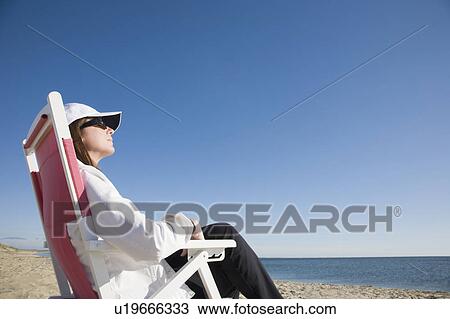 Stock Image - Woman relaxing at the beach. Fotosearch