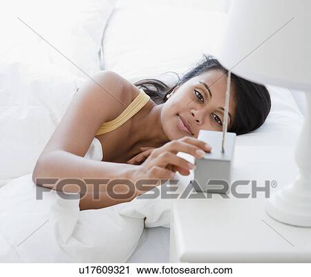 Stock Image - Woman setting alarm clock. Fotosearch