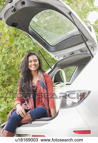 Stock Image - Woman sitting in trunk of car. Fotosearch