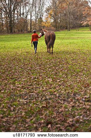 Stock Image - Woman walking with horse. Fotosearch