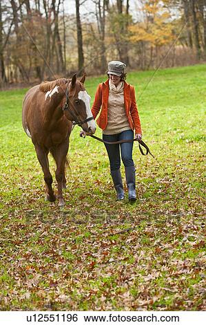 Stock Photograph - Woman walking with horse. Fotosearch