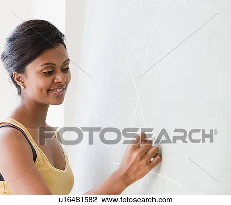Stock Image - Woman writing on chalkboard. Fotosearch