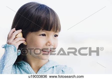 Stock Photograph - Young girl holding seashell. Fotosearch