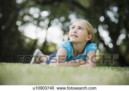 Young girl lying on grass View Large Photo Image Stock Image - Young girl lying on grass. Fotosearch