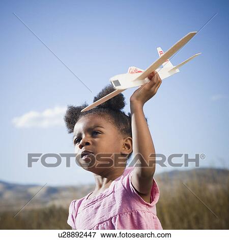 Stock Photo - Young girl playing with toy airplane. Fotosearch