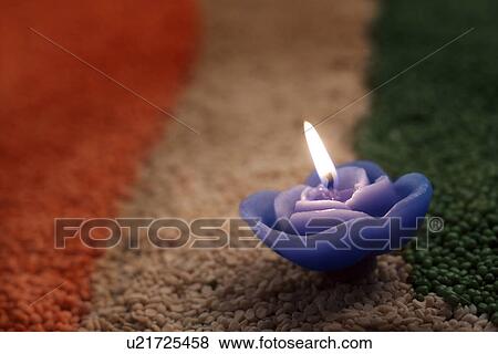 Stock Photo - A candle in the middle of coloured pulses. Fotosearch