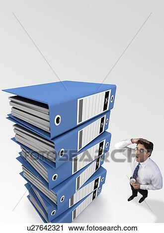 Businessman tensed after looking at a stack of files View Large Photo Image Stock Image - Businessman tensed after looking at a stack of files. Fotosearch