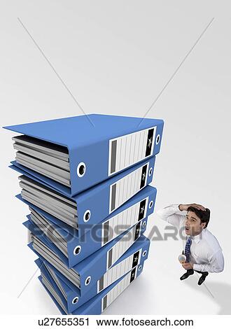 Businessman tensed after looking at a stack of files View Large Photo Image Stock Image - Businessman tensed after looking at a stack of files. Fotosearch