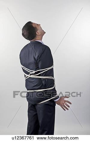 Stock Image - Businessman tied up with rope. Fotosearch